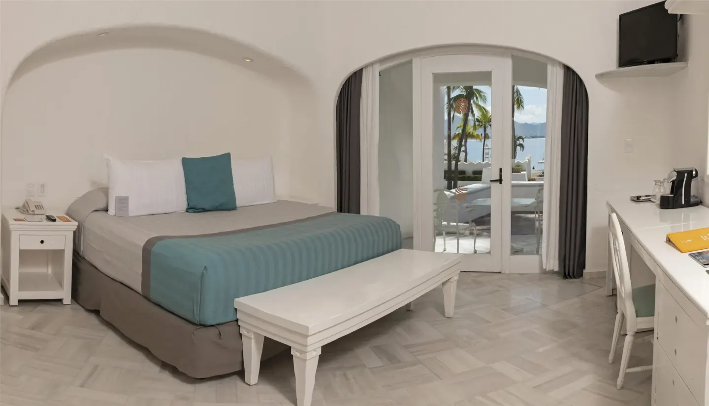 King bed guest room with terrace doors and water view at Las Hadas.