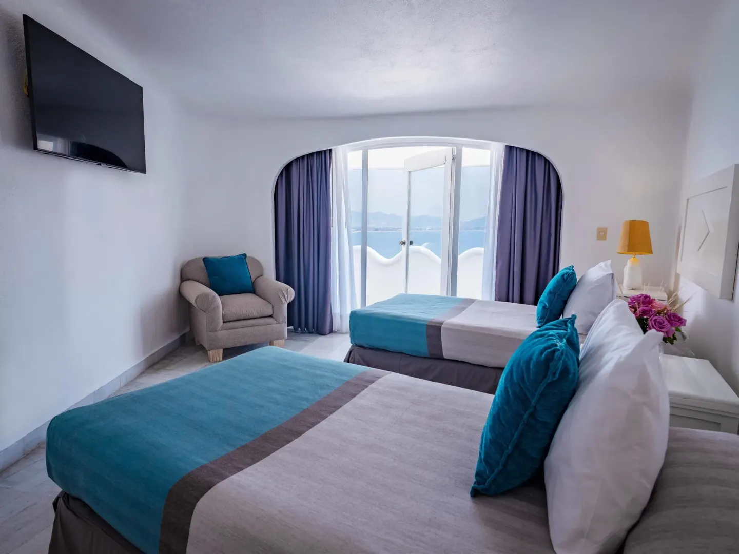 Guest room with two beds, balcony doors, and bay view at Las Hadas.