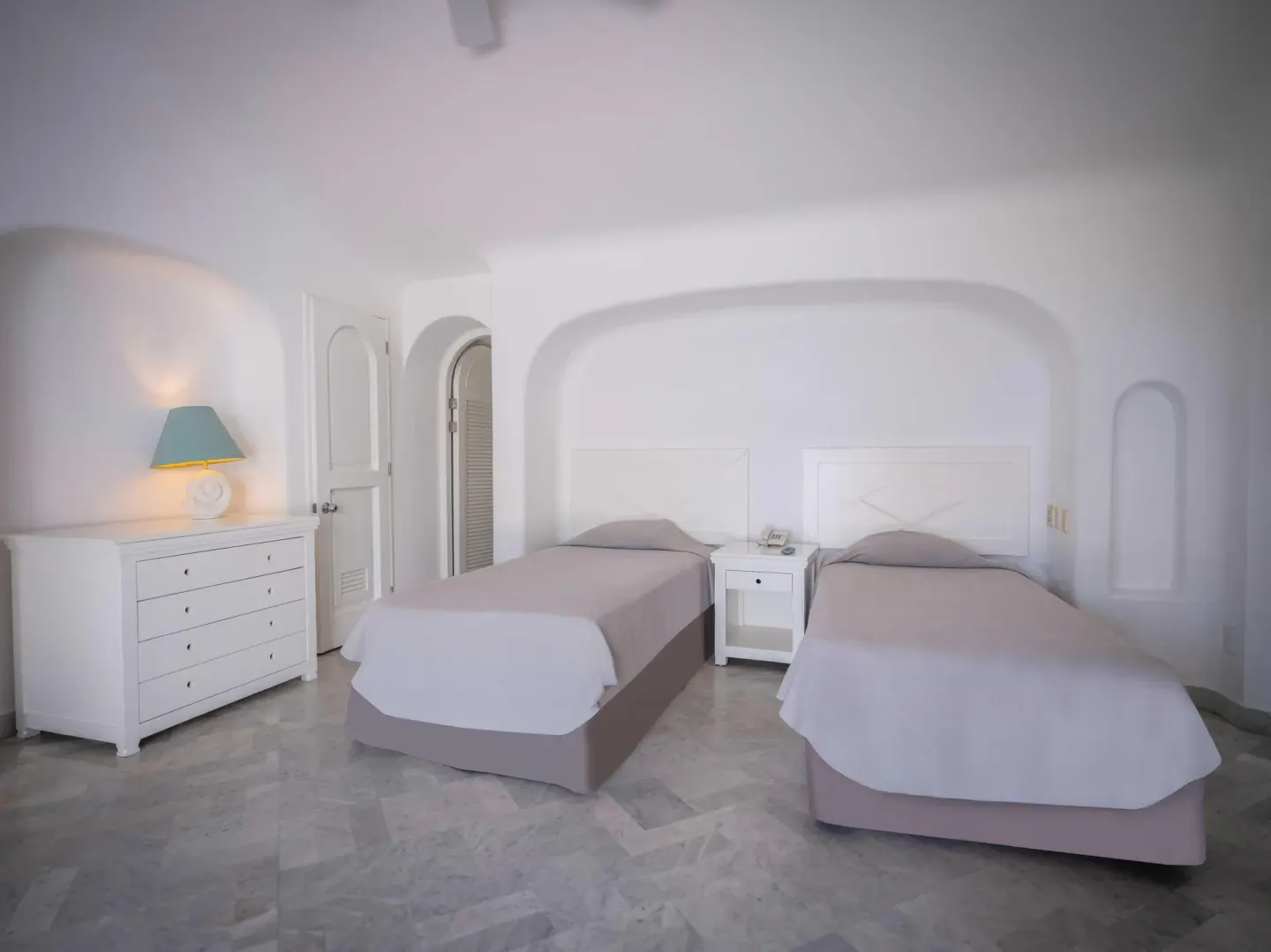 Double bed guest room with two beds and white arched walls at Las Hadas.