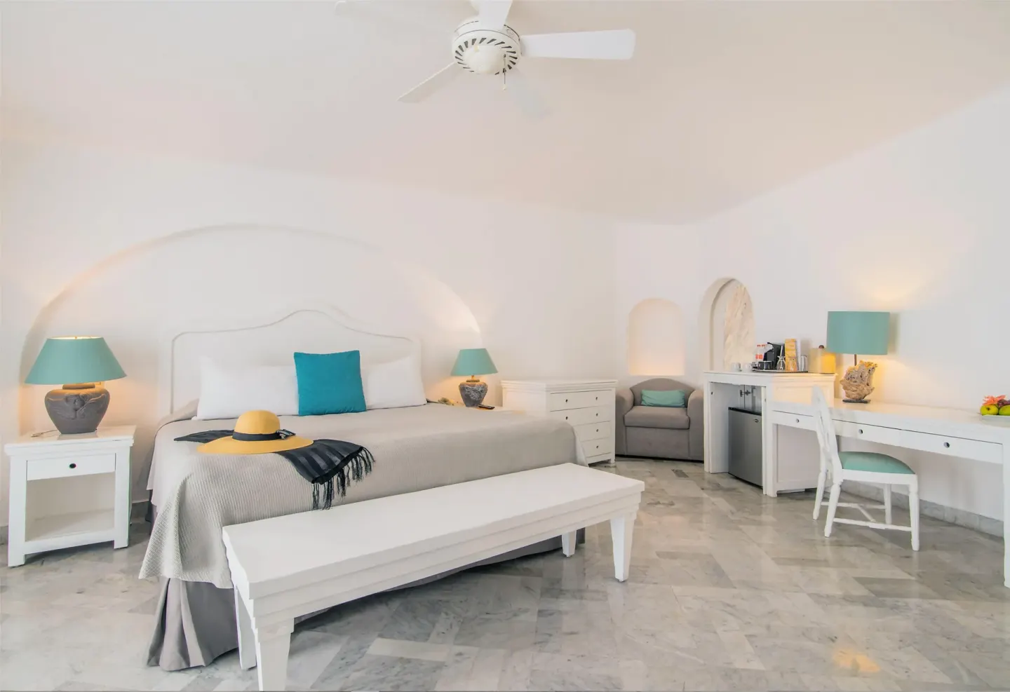 King bed guest room with white furniture and turquoise accents at Las Hadas.