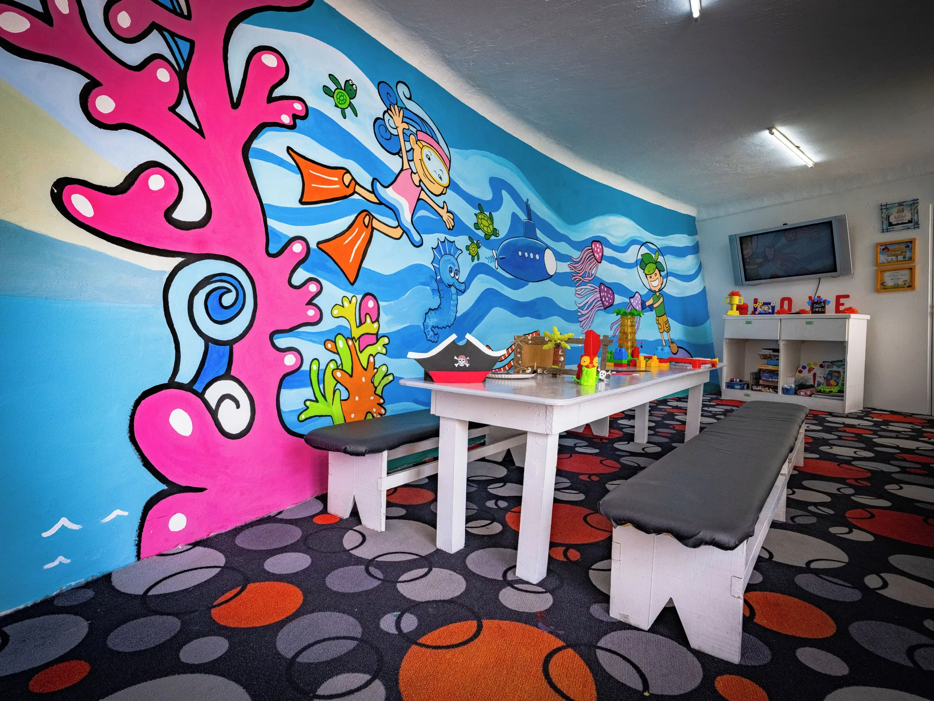 Kids club room with underwater mural, tables, benches and toys at Las Hadas.