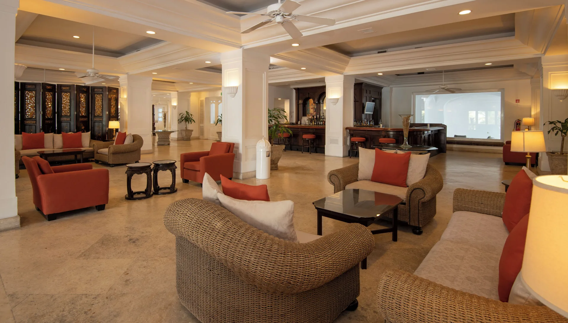 Spacious lounge with wicker seating, red chairs, bar area, and projection screen at Las Hadas.