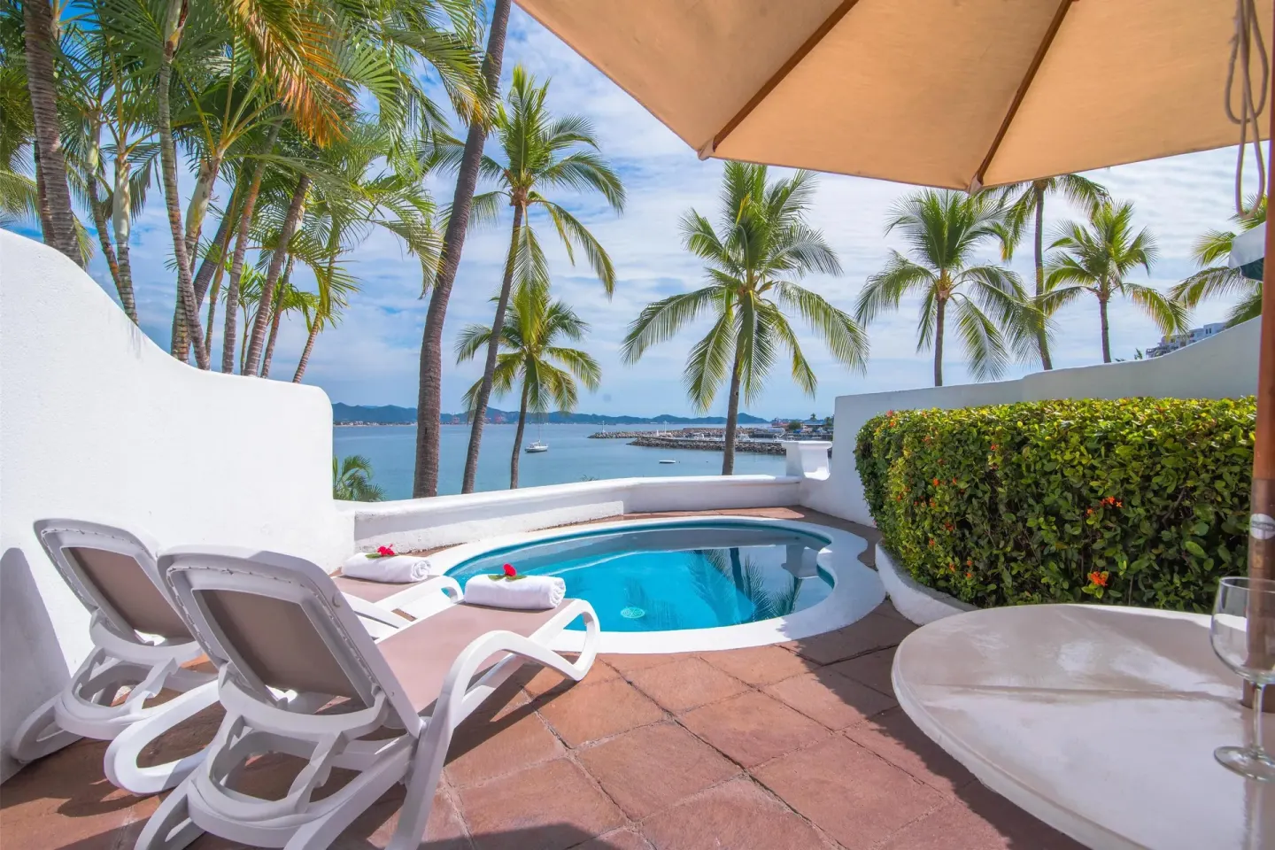 Private plunge pool terrace with loungers and palm-framed bay view at Las Hadas.