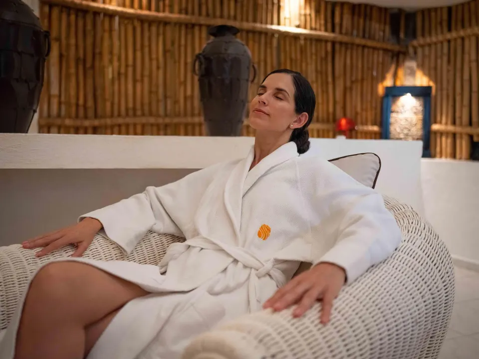 Guest in a white robe relaxing in a wicker chair at Las Hadas.
