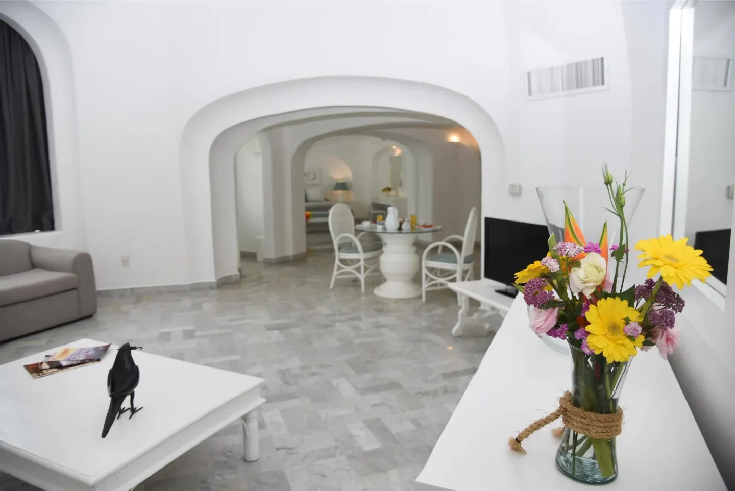 Suite living room with sofa, coffee table, dining area, and flowers at Las Hadas.