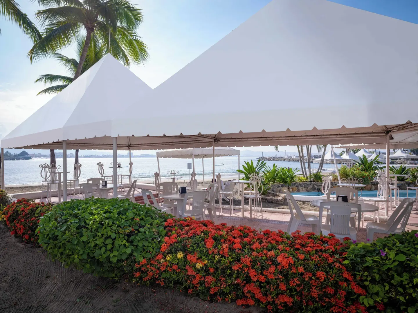 Beachside seating under white canopy tents beside the water at Las Hadas.