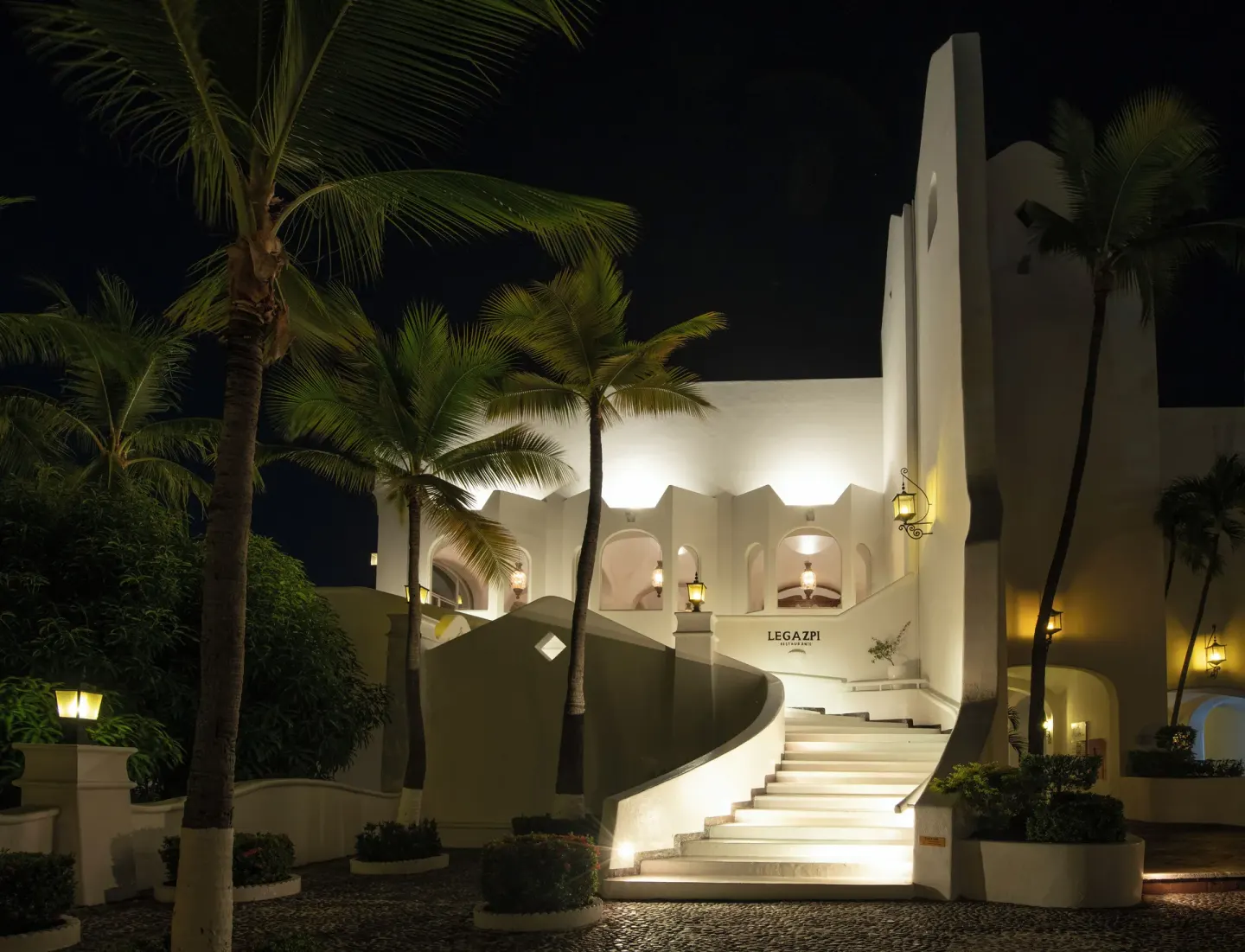 Illuminated Legazpi entrance with stairs and palms at Las Hadas.