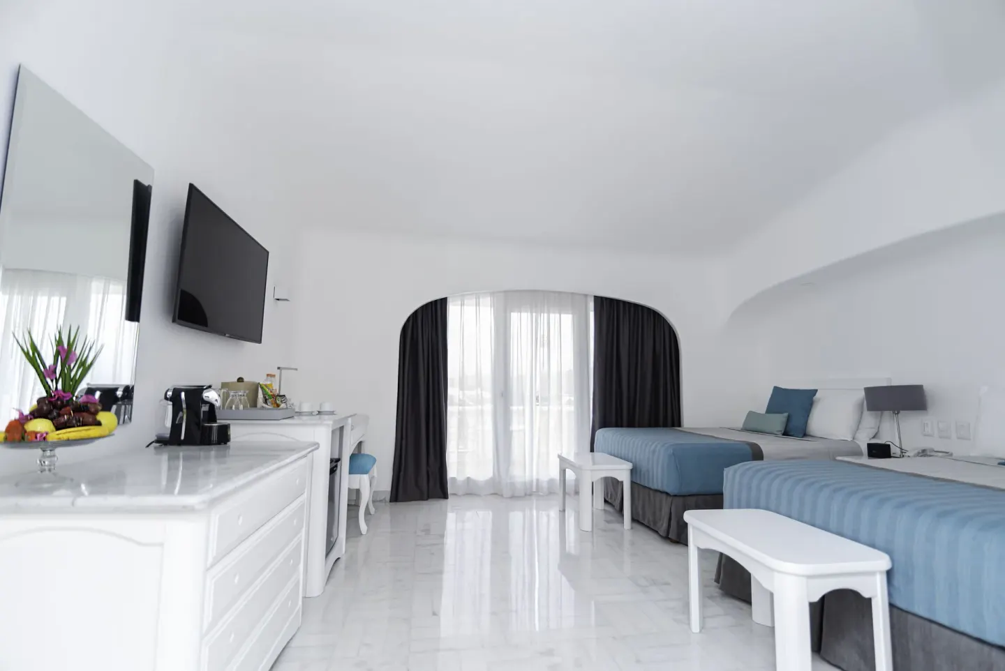Brisas Beach Club room with two beds, dresser, TV, and balcony curtains at Las Hadas.