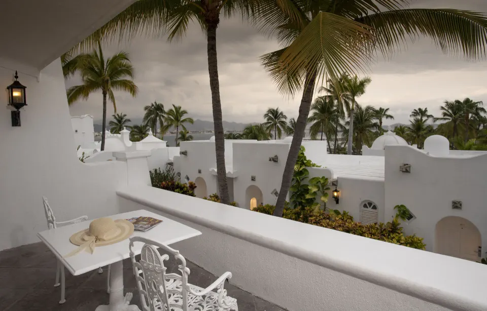 Deluxe Room balcony with table, chairs, palms and white rooftops at Las Hadas.