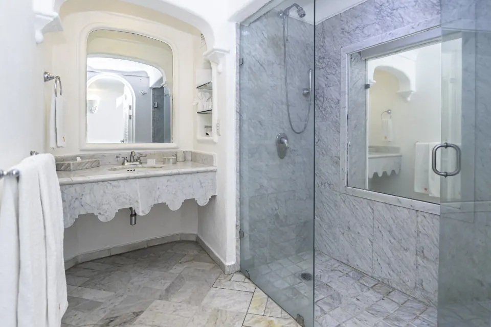 Deluxe Room bathroom with marble vanity and glass shower at Las Hadas.