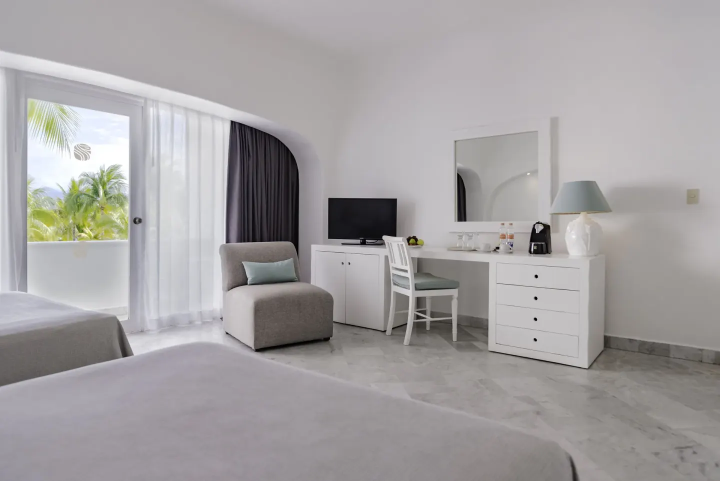 Deluxe Room seating area with balcony, desk, TV and dresser at Las Hadas.