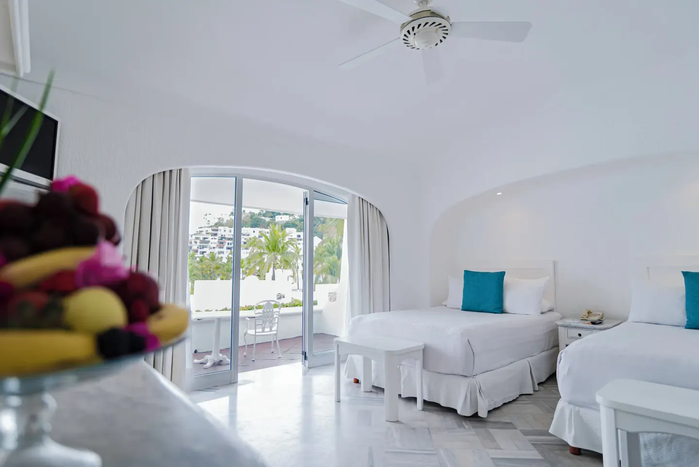 Deluxe Room with two beds, open balcony doors and palm views at Las Hadas.