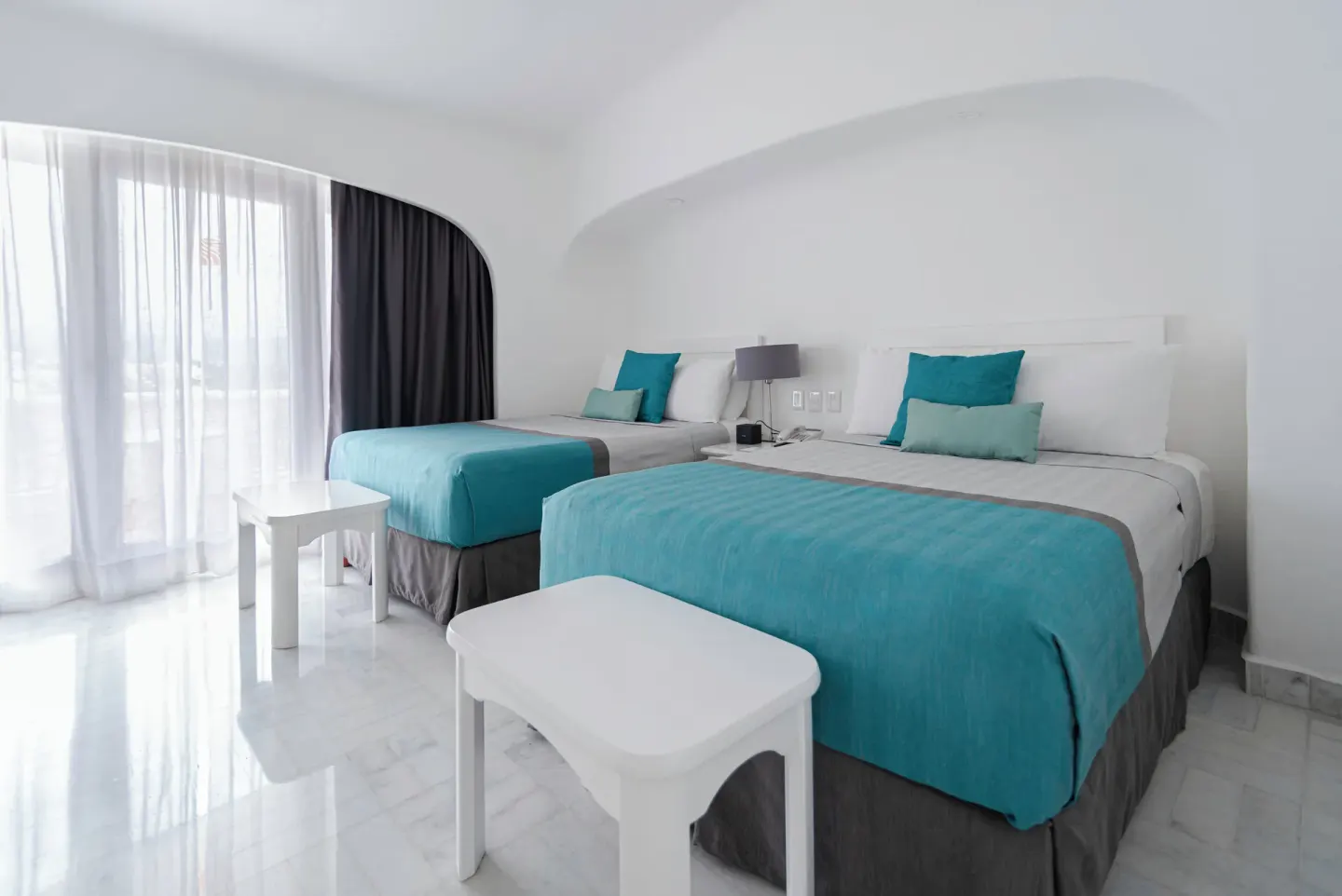 Deluxe Room with two beds, turquoise accents and balcony curtains at Las Hadas.