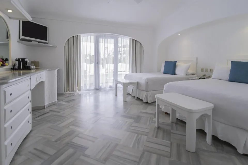 Deluxe Room with two beds, vanity and curtained balcony doors at Las Hadas.