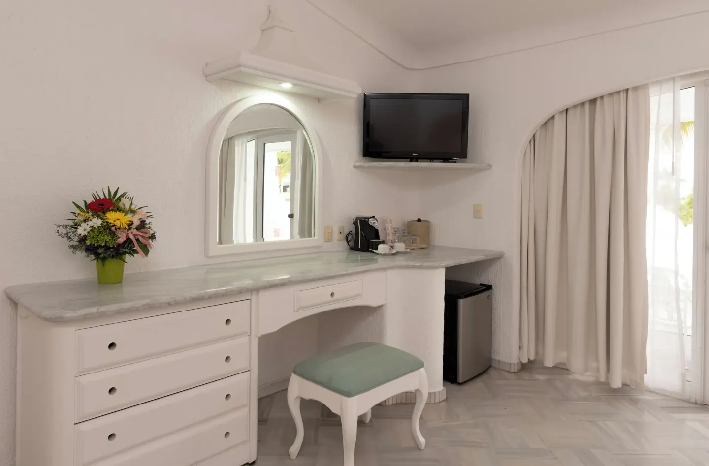Deluxe Room vanity wall with TV, dresser, stool and balcony curtains at Las Hadas.