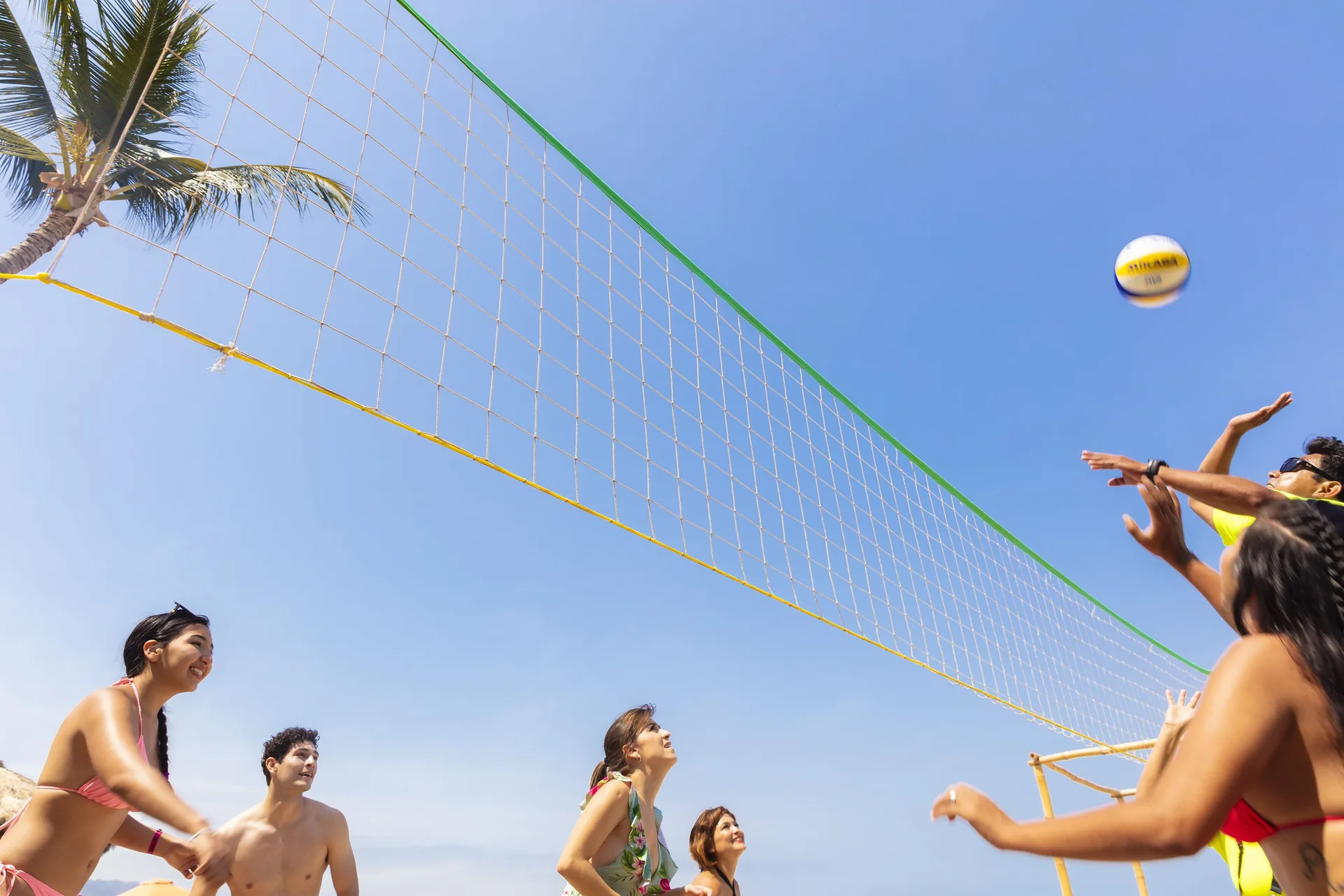 Guests playing beach volleyball under a clear sky at Las Palmas by the Sea.