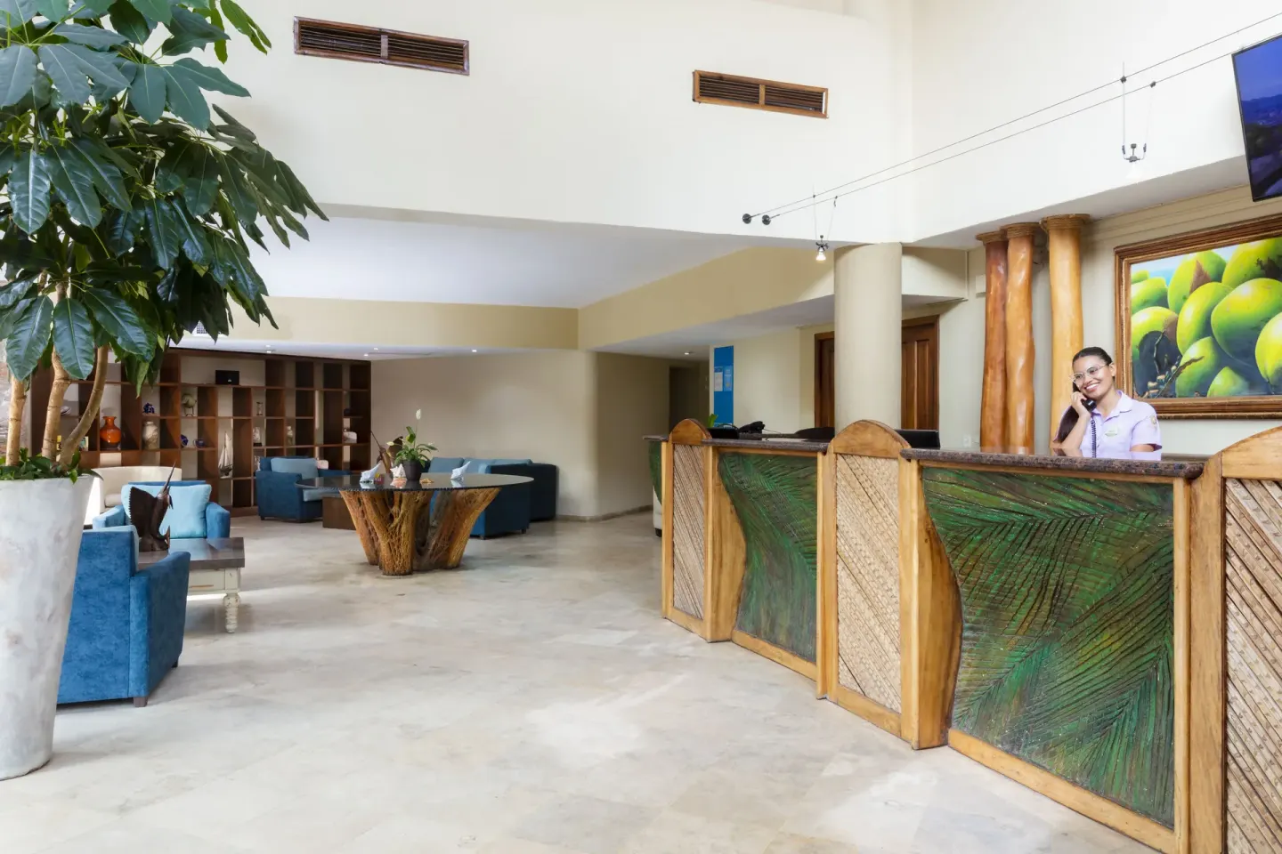 Lobby reception desk at Las Palmas by the Sea with lounge seating and a staff member.