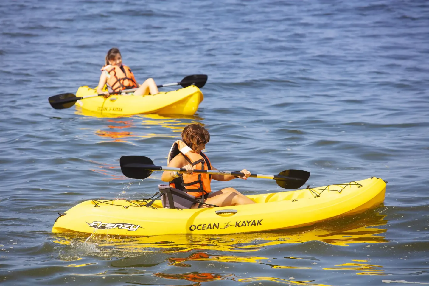 Two guests paddling yellow kayaks on the ocean at Las Palmas by the Sea.