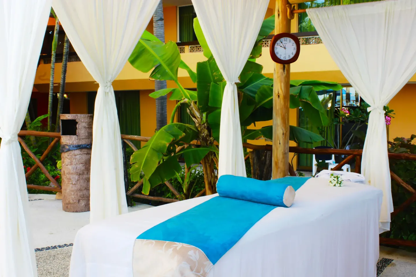 Outdoor massage bed with white curtains and turquoise linens at Las Palmas by the Sea.