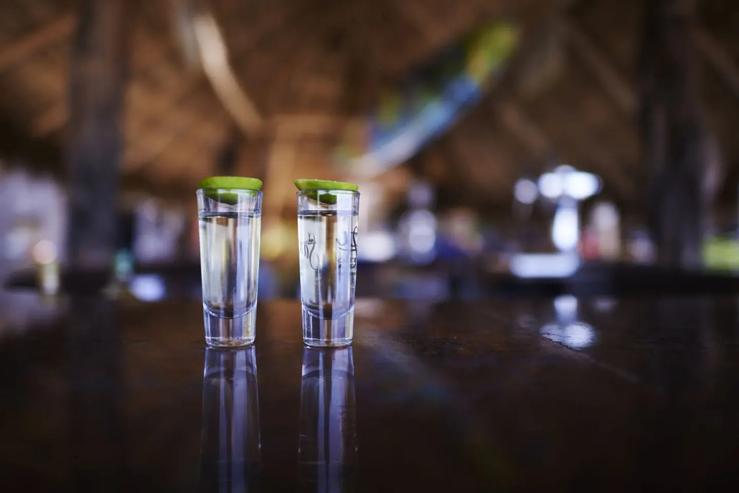 Two clear drinks with lime on a dark bar counter at Las Palmas by the Sea.