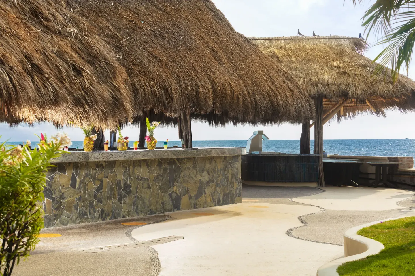 Seaside palapa bar with stone counter and ocean beyond at Las Palmas by the Sea.