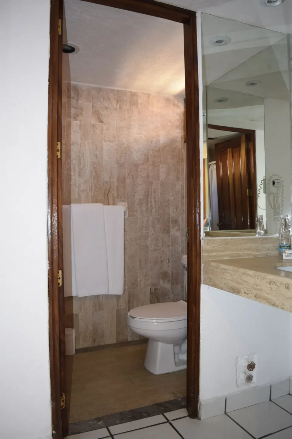 Standard Room bathroom doorway with toilet, towels, vanity edge, mirror, and hair dryer at Las Palmas by the Sea.