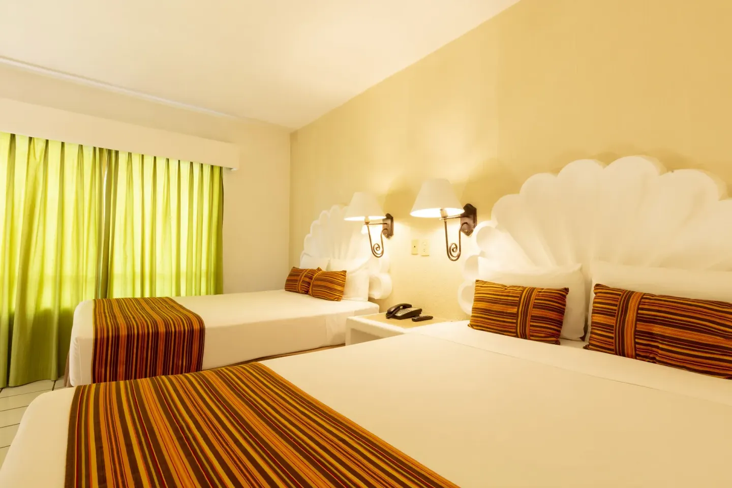Standard Room with two beds, green curtains, shell headboards, and bedside lamps at Las Palmas by the Sea.
