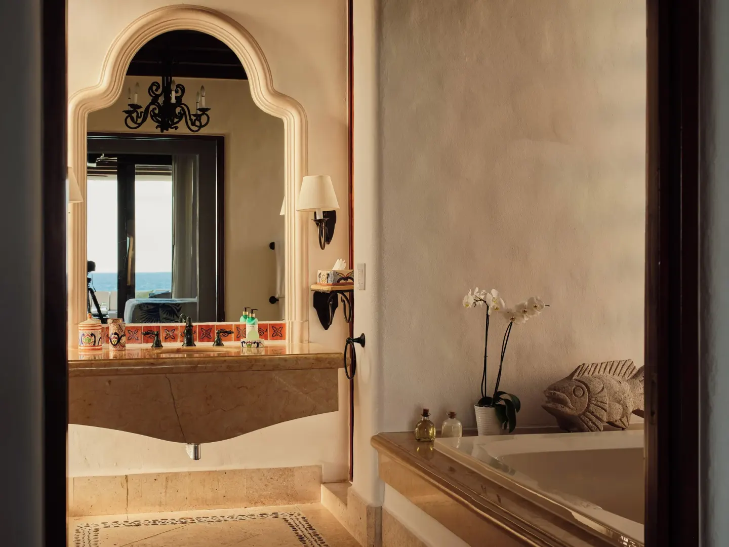 Bathroom with arched mirror, tub, and ocean glimpse at Las Ventanas al Paraiso.