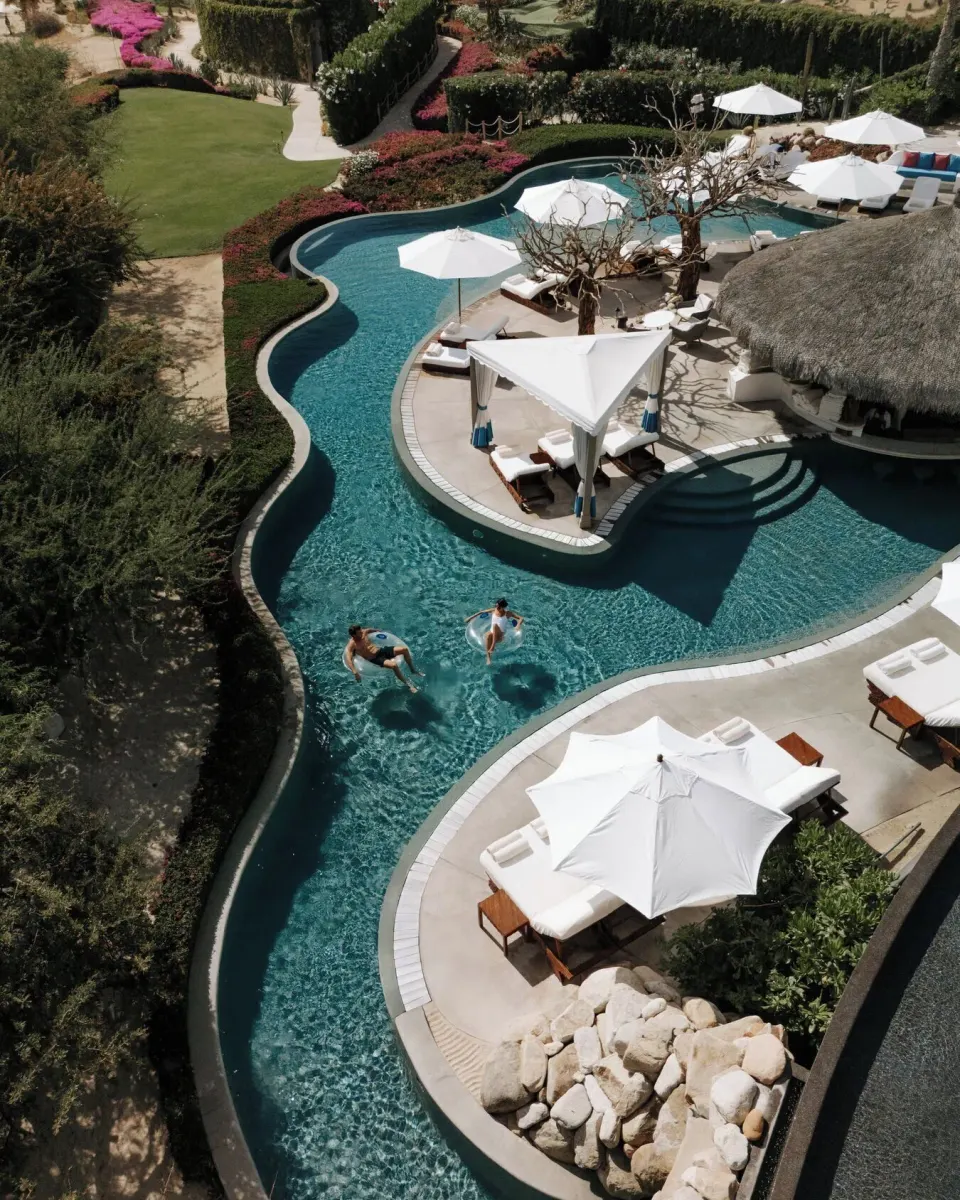 Curving resort pool with white umbrellas and loungers at Las Ventanas al Paraiso.