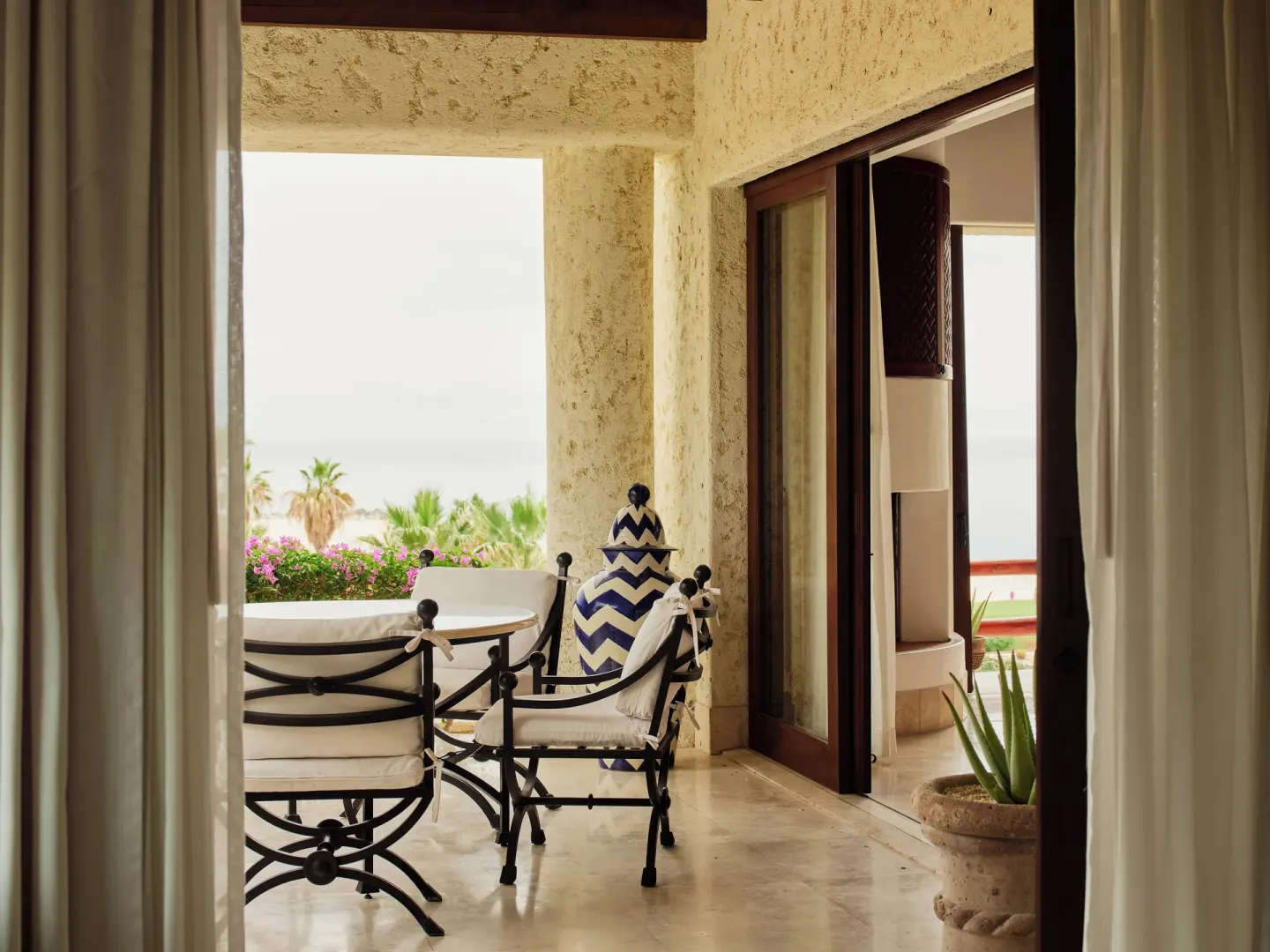 Guest terrace with iron chairs, ceramic jar, and ocean glimpse at Las Ventanas al Paraiso.