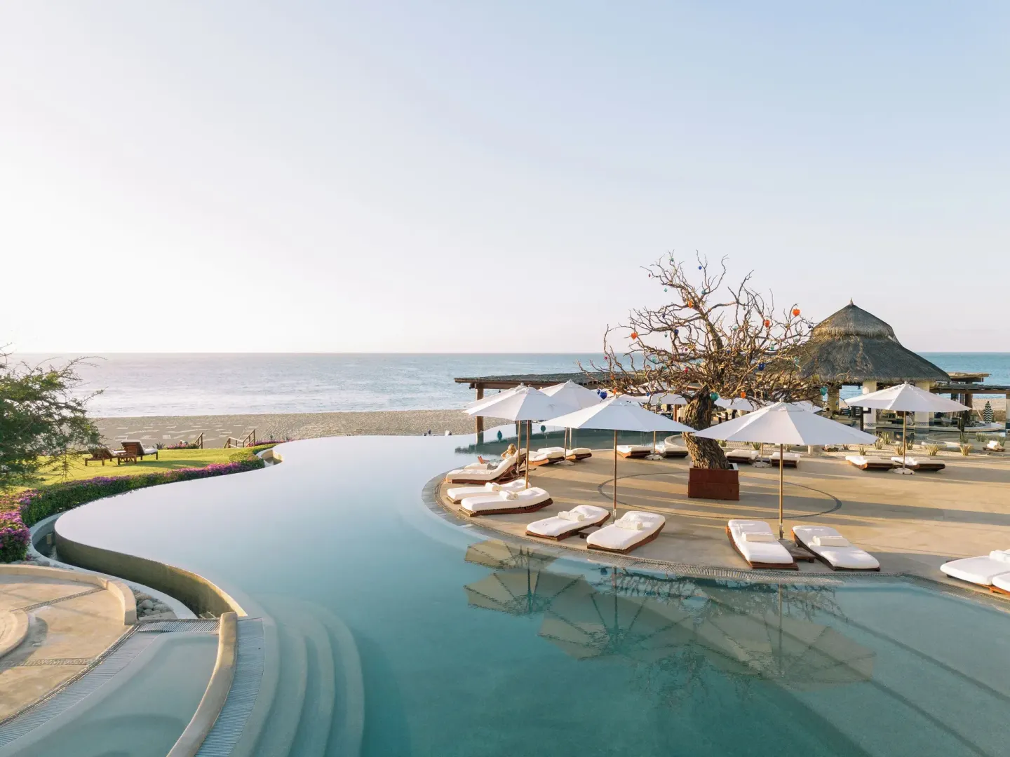 Infinity pool with loungers, white umbrellas, and ocean beyond at Las Ventanas al Paraiso.