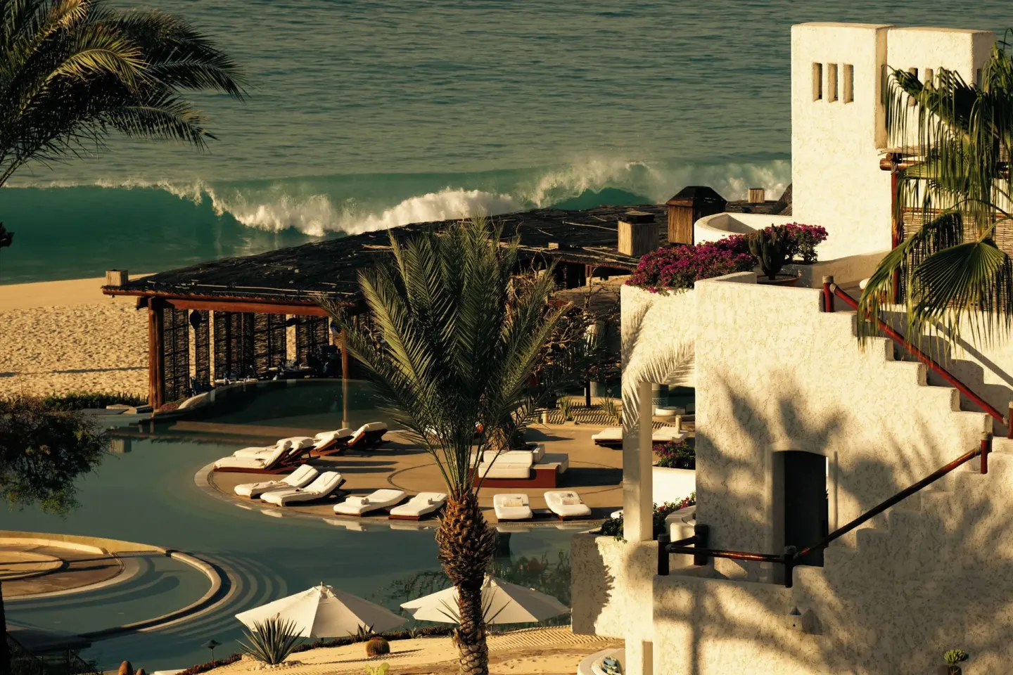 Oceanfront pool area with palms and white resort buildings at Las Ventanas al Paraiso.