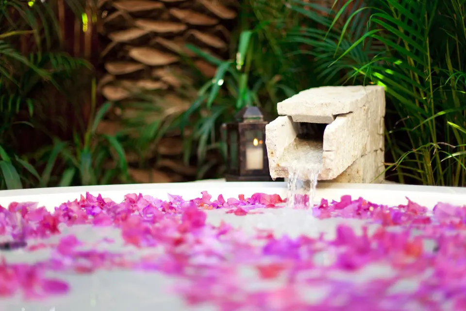 Petal-filled soaking tub with a stone water spout at Las Ventanas al Paraiso.