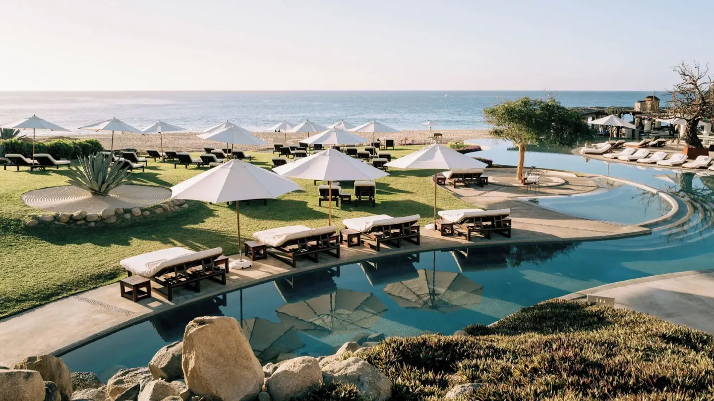 Pool lawn with loungers, white umbrellas, and beach beyond at Las Ventanas al Paraiso.