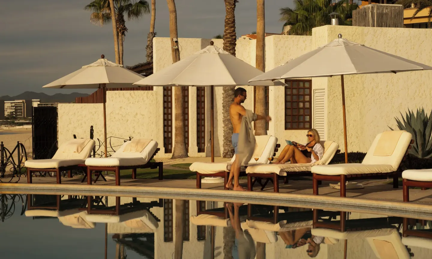 Guests relax on loungers beside a reflective pool at Las Ventanas al Paraiso.