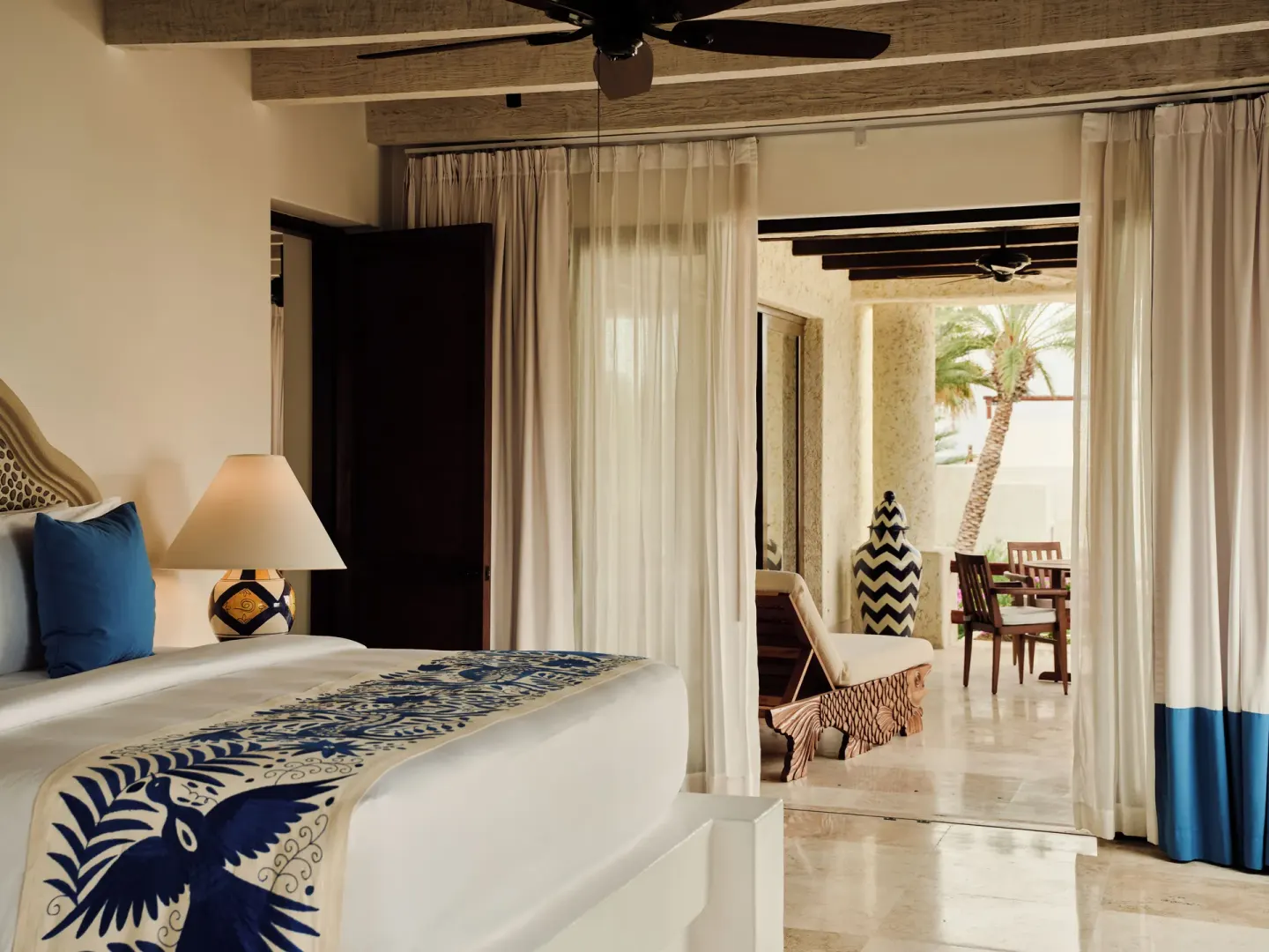 King bed with blue patterned runner and terrace beyond at Las Ventanas al Paraiso.