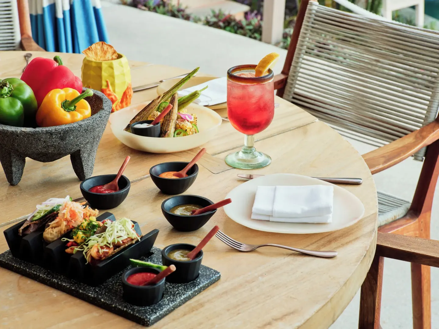 Colorful tacos, sauces, peppers, and a red drink on a table at Las Ventanas al Paraiso.