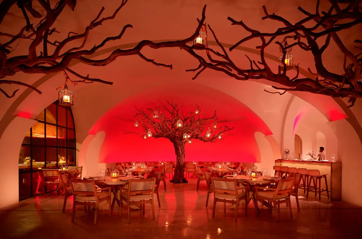 A red-lit restaurant interior with sculptural trees at Las Ventanas al Paraiso.