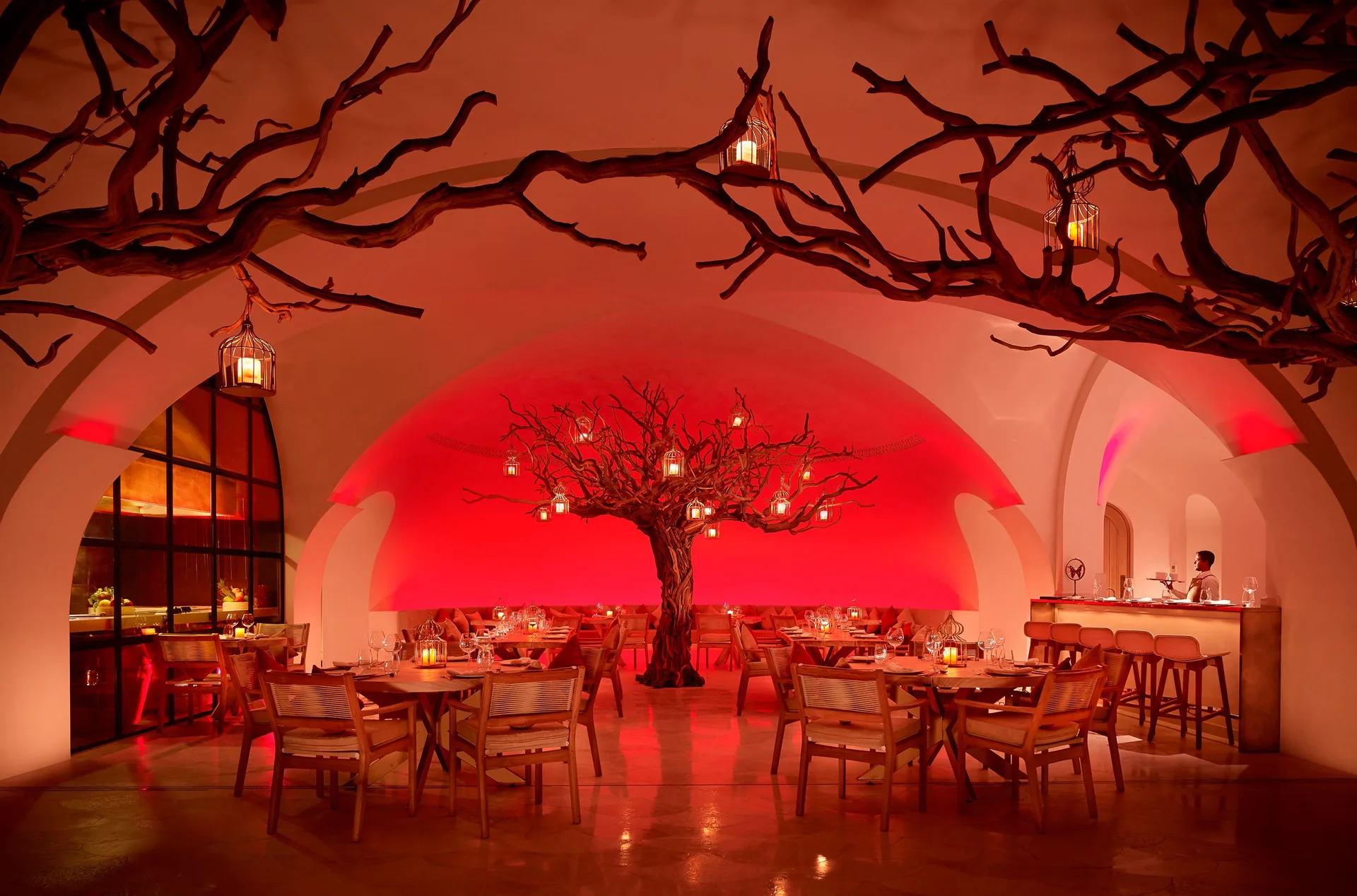 A red-lit restaurant interior with sculptural trees at Las Ventanas al Paraiso.