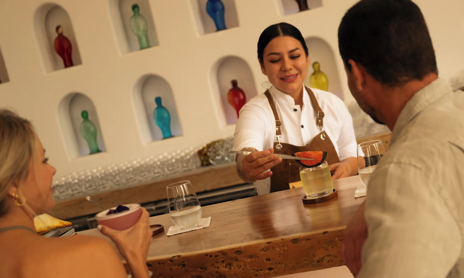A bartender garnishes cocktails for guests at La Botica at Las Ventanas al Paraiso.