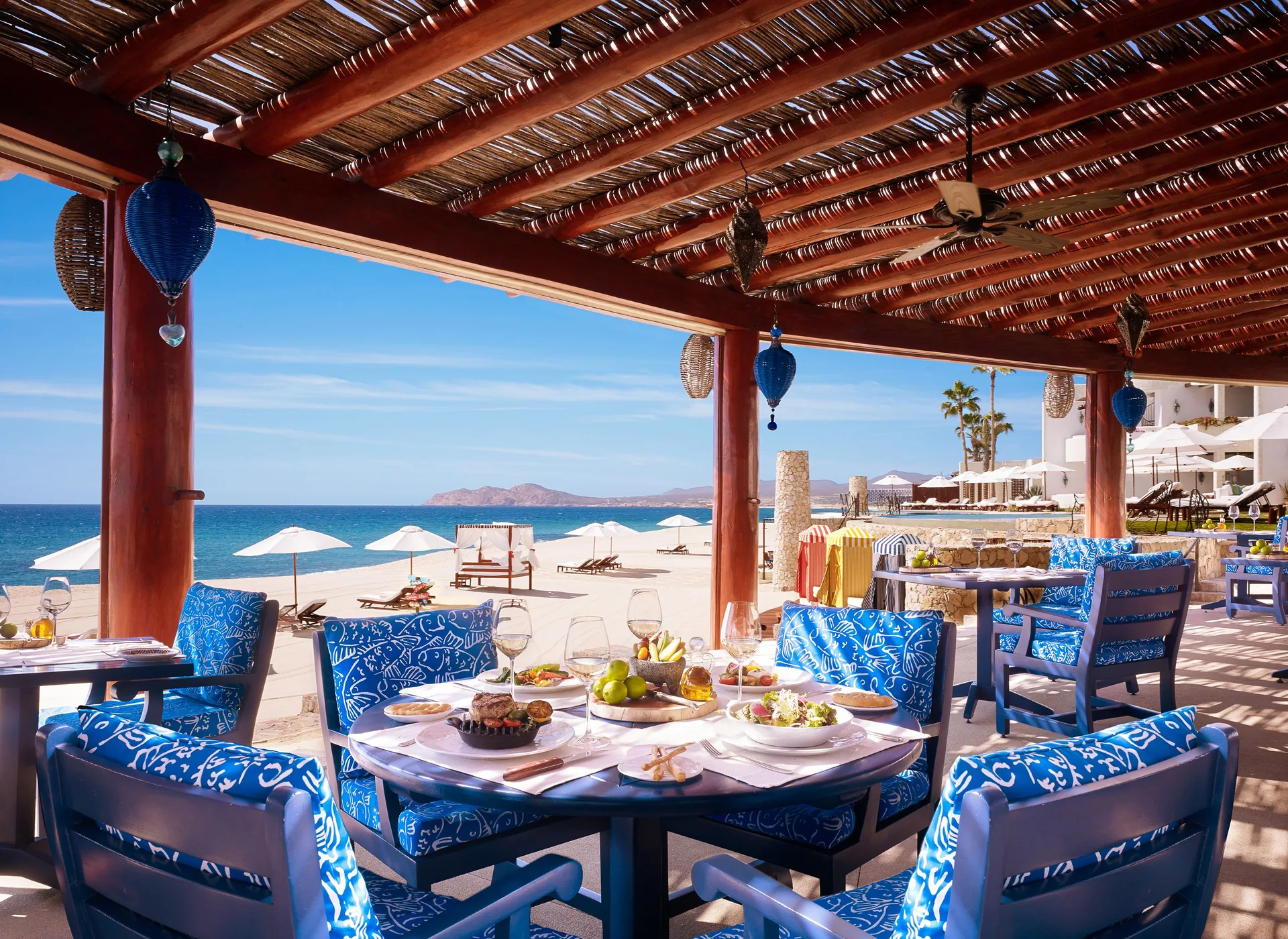 Beachfront terrace dining with blue chairs and ocean views at Las Ventanas al Paraiso.