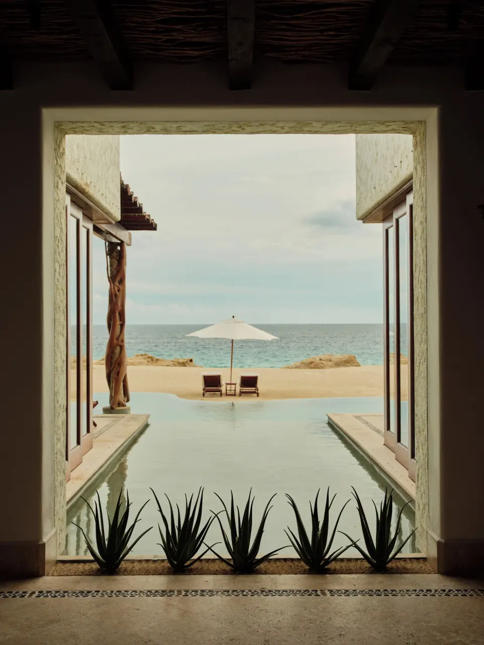 Pool, umbrella, beach, and ocean framed from a villa doorway at Las Ventanas al Paraiso.