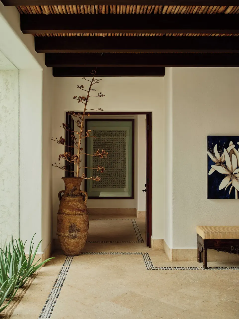 Villa hallway with a large rustic vase and wall art at Las Ventanas al Paraiso.