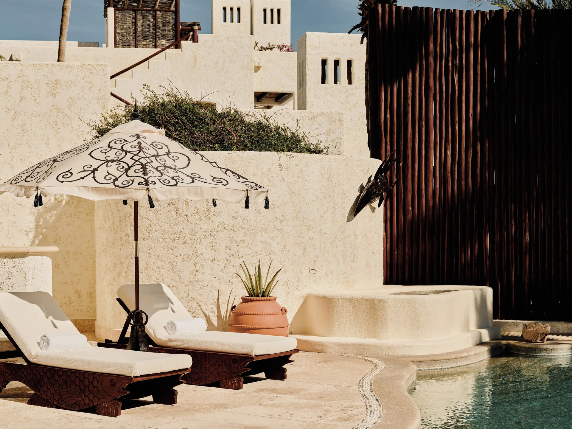 Pool terrace of a One Bedroom Oceanfront Villa at Las Ventanas al Paraiso with loungers and umbrella.