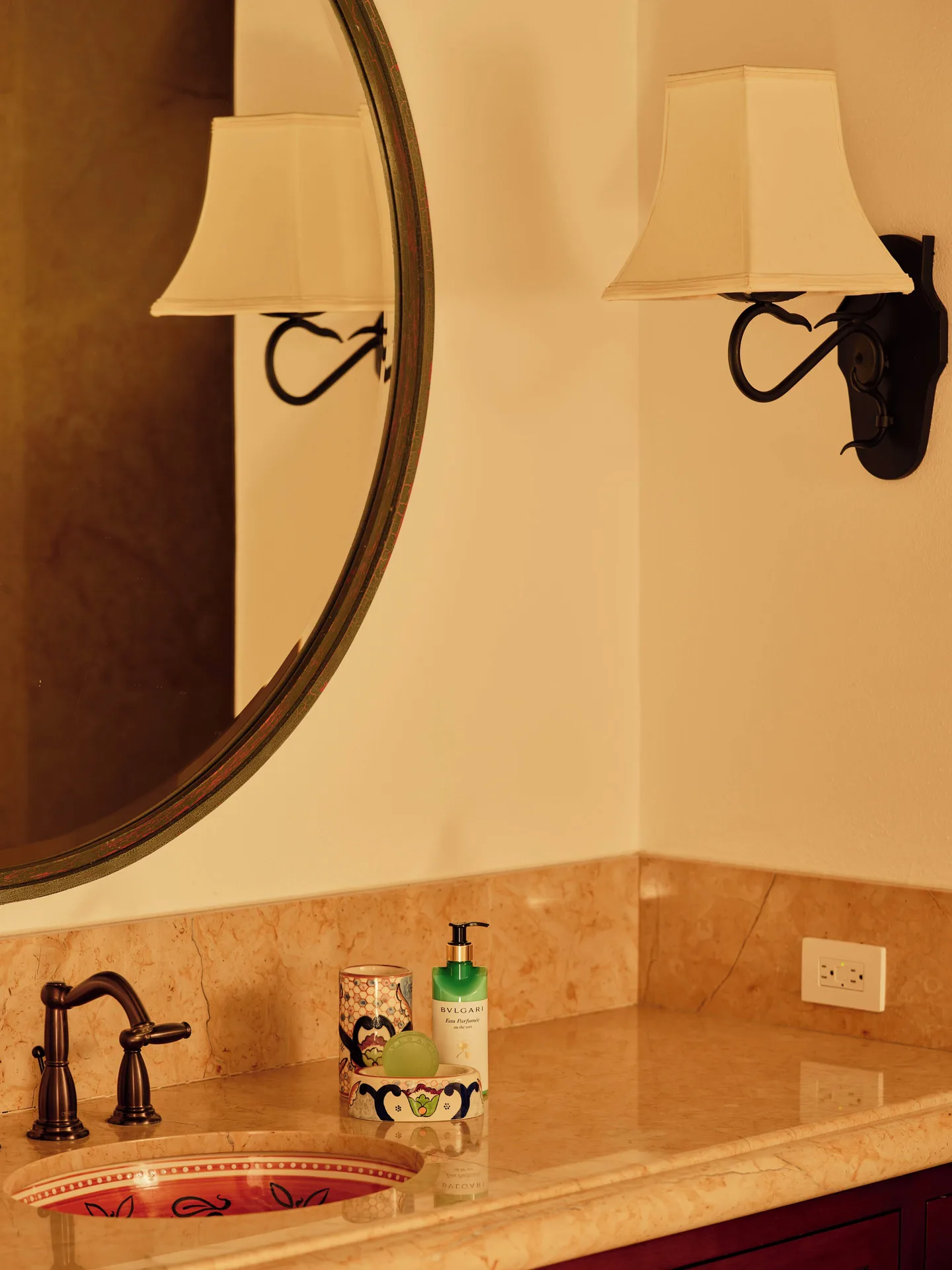 Marble vanity with round mirror and wall sconce at Las Ventanas al Paraiso.