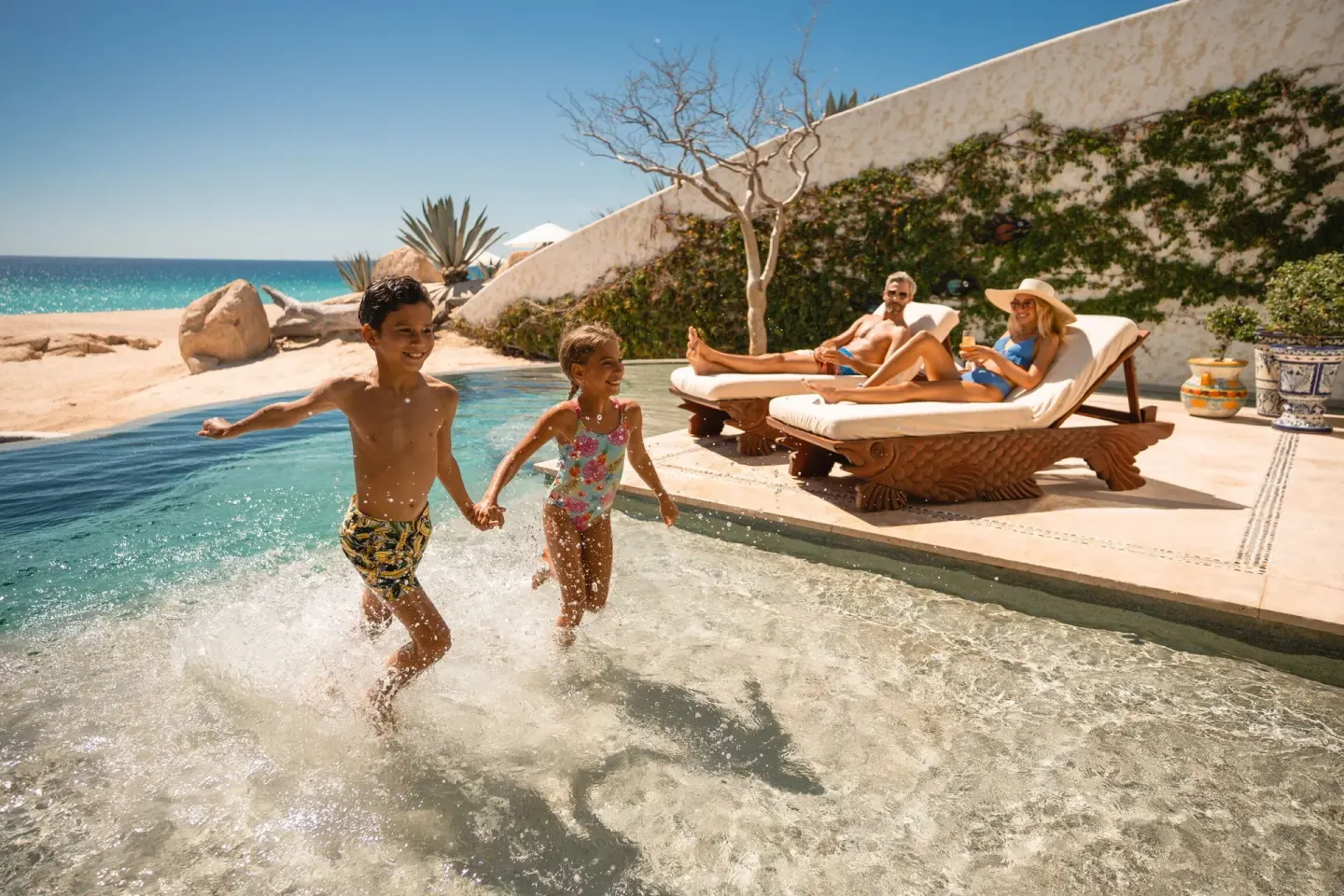 Children splash in a beachfront villa pool with lounge chairs at Las Ventanas al Paraiso.