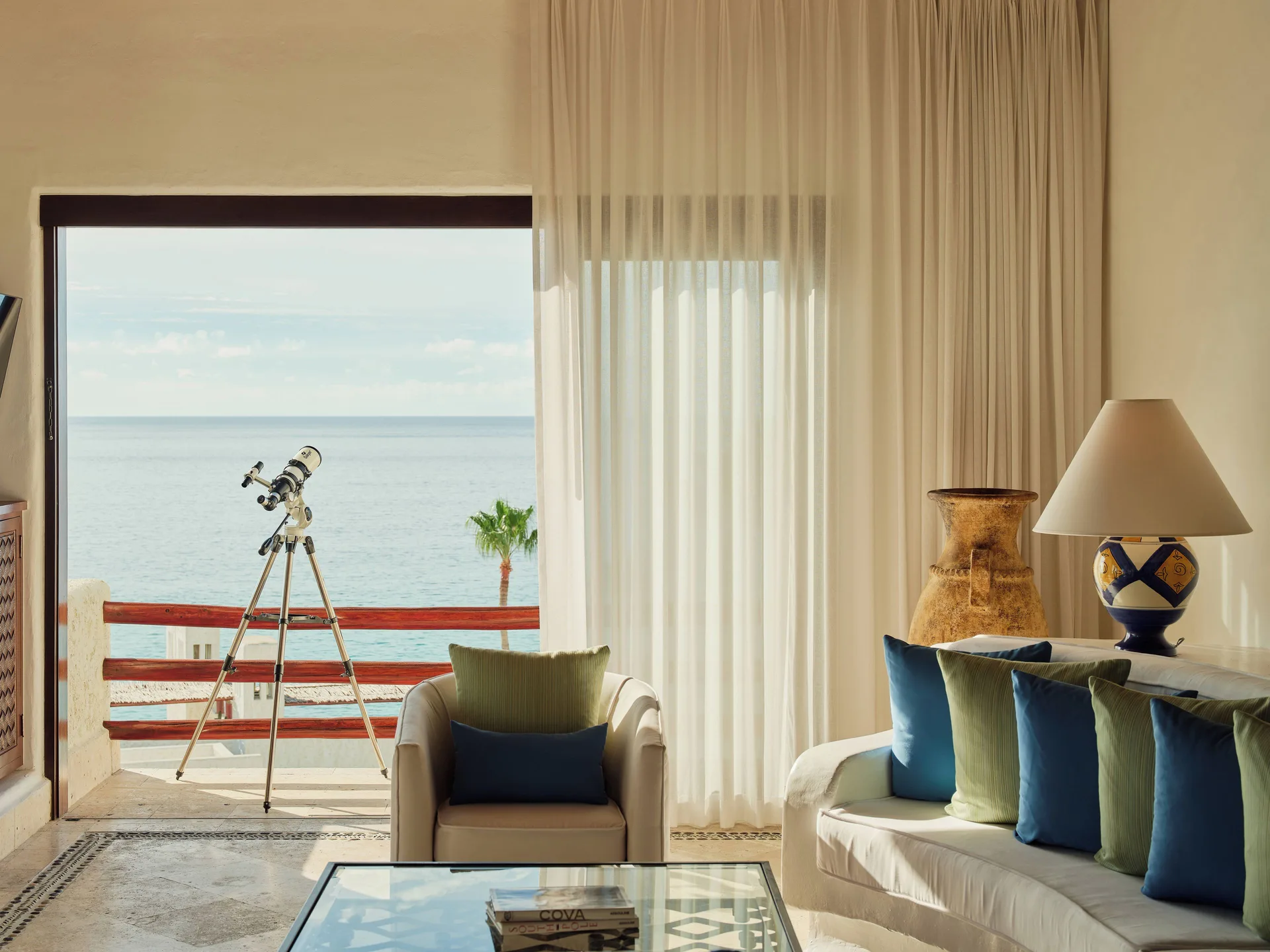 Oceanview living room with sofa, armchair, telescope and balcony at Las Ventanas al Paraiso.