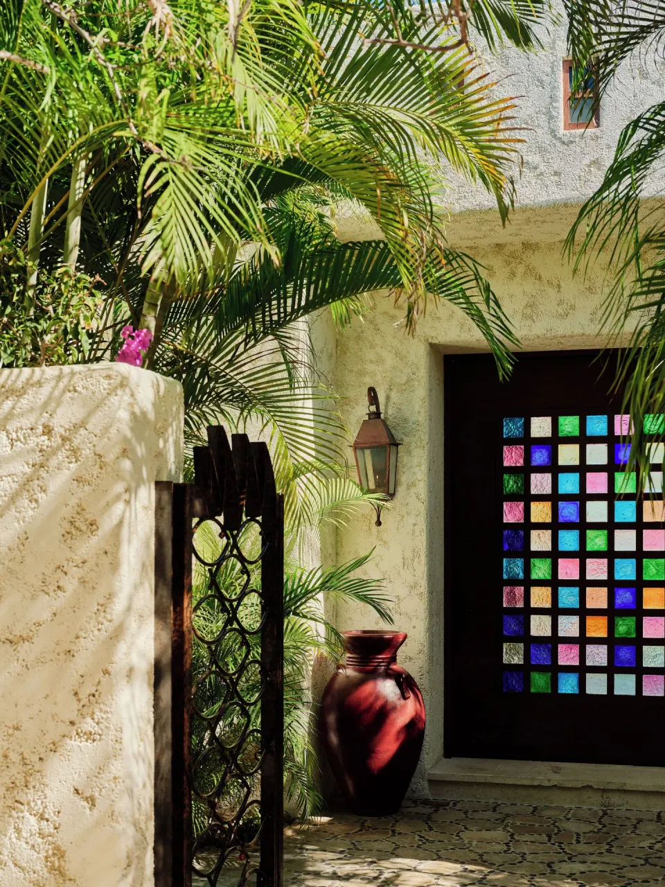 Villa entry gate with palms, lantern and colorful glass door at Las Ventanas al Paraiso.