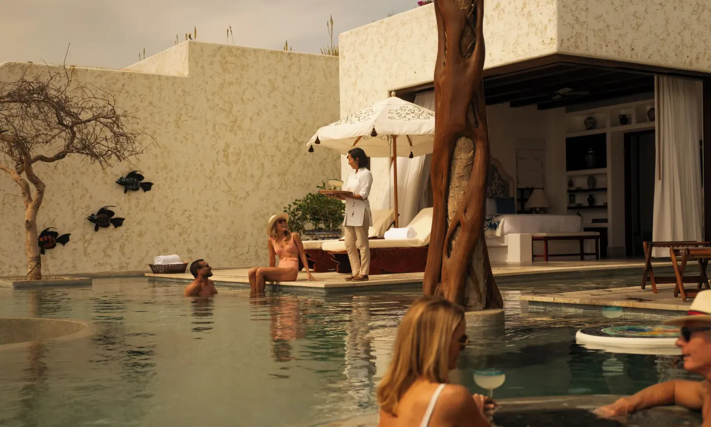 Guests in a private villa pool beside loungers and open interiors at Las Ventanas al Paraiso.
