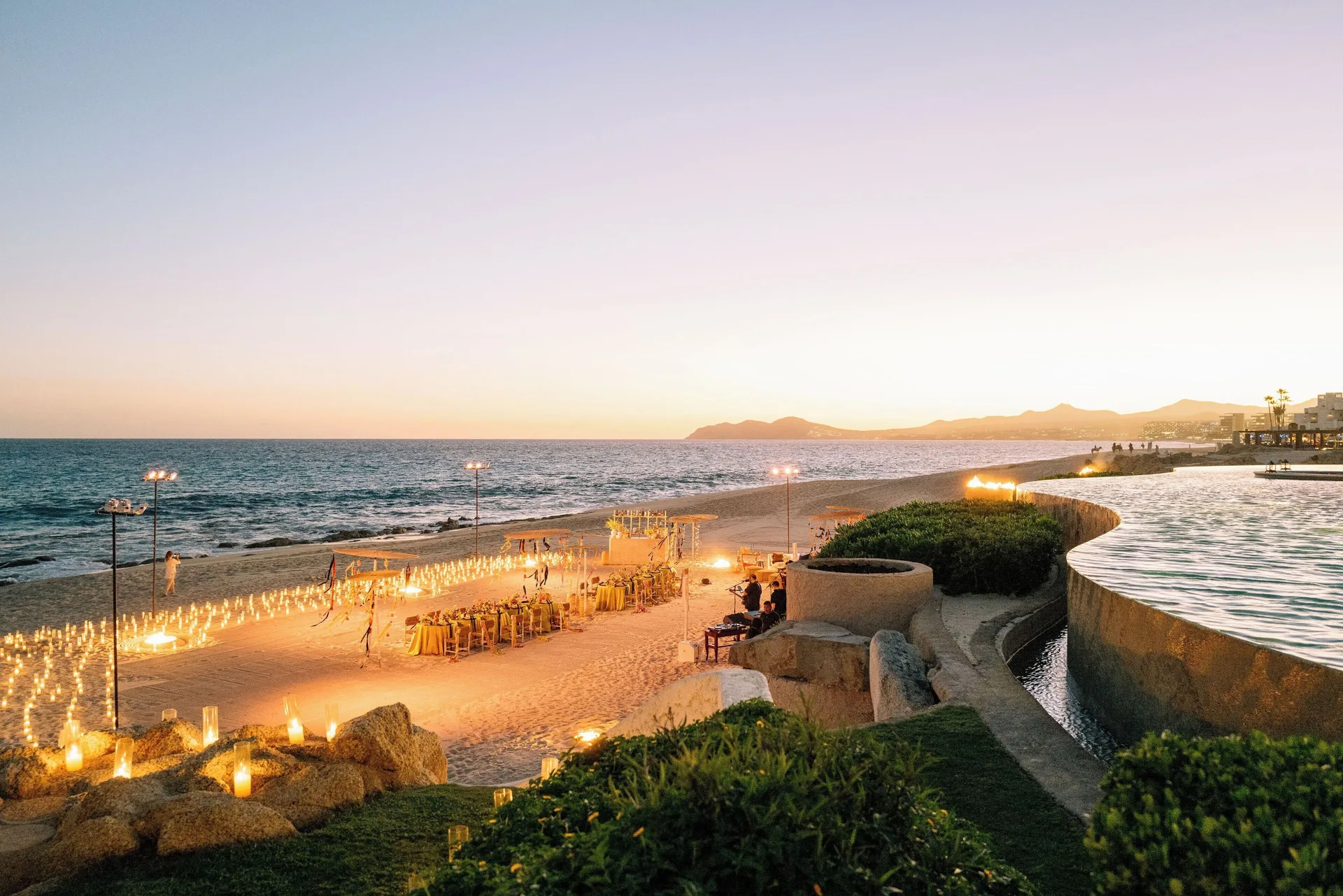 Beachfront event setup with candles beside the ocean at sunset at Las Ventanas al Paraiso.